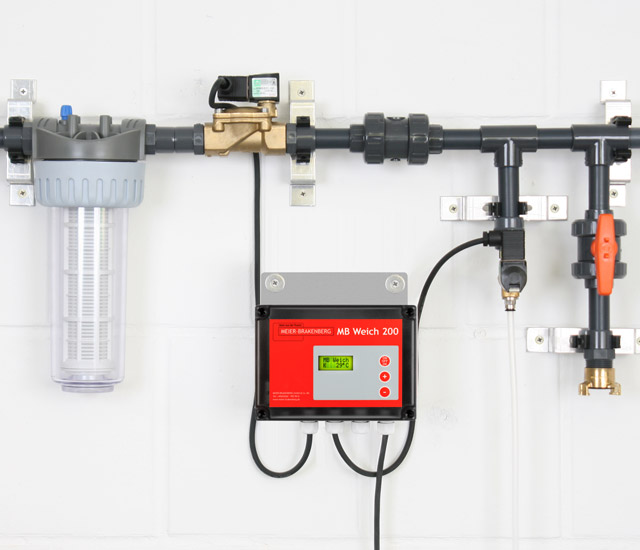 Die Verteilung der Einweich- und Kühlanlage beinhaltet den Wasserfilter, das Magnetventil, die Druckentlastung der Kühlung und den optionalen Desinfektionsanschluss. Mittig sitzt der Einweich- und Kühlautomat MBWeich 200